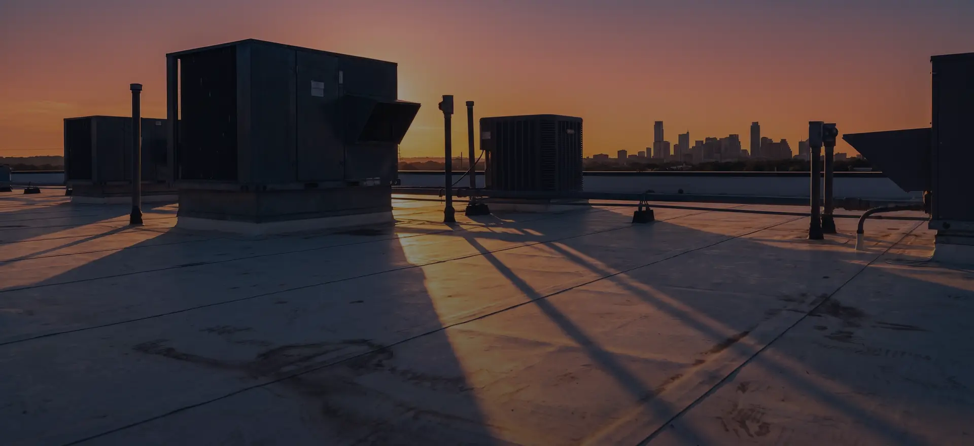 Commercial rooftop HVAC units at dusk with the Austin, Texas skyline